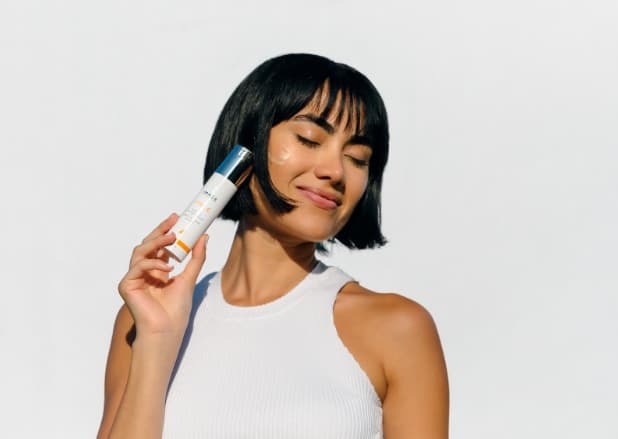 A happy woman holding a bottle of Image Skincare A happy woman holding a bottle of Image Skincare