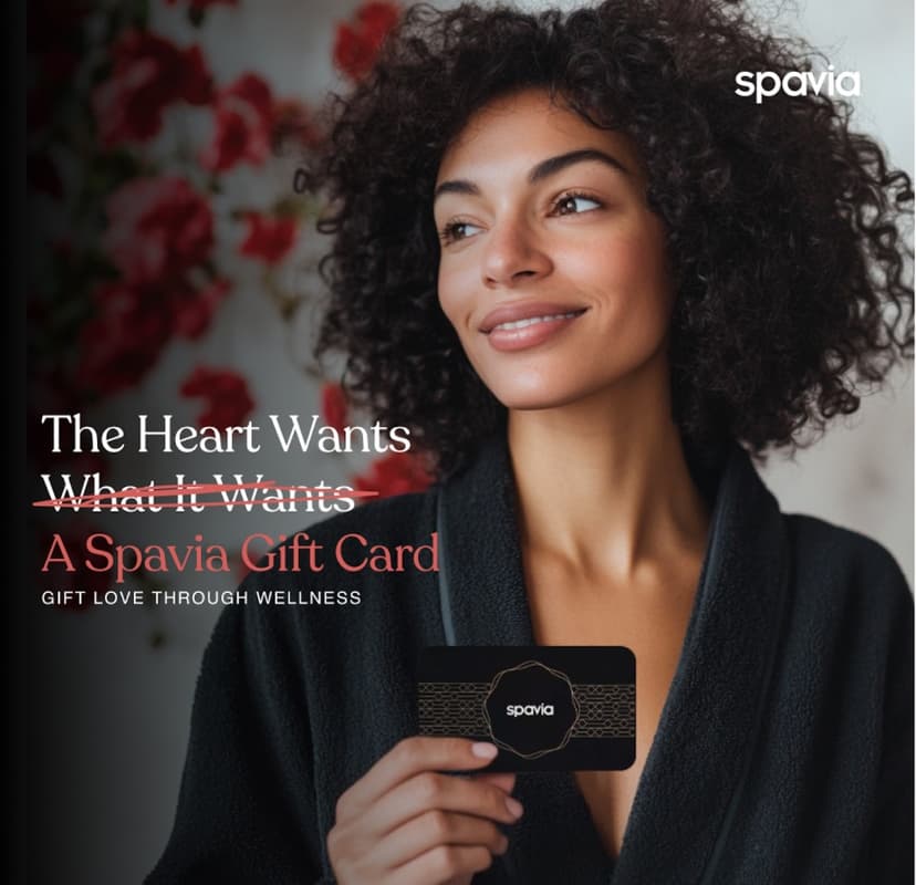 A happy woman in a robe holding a Spavia gift card A happy woman in a robe holding a Spavia gift card